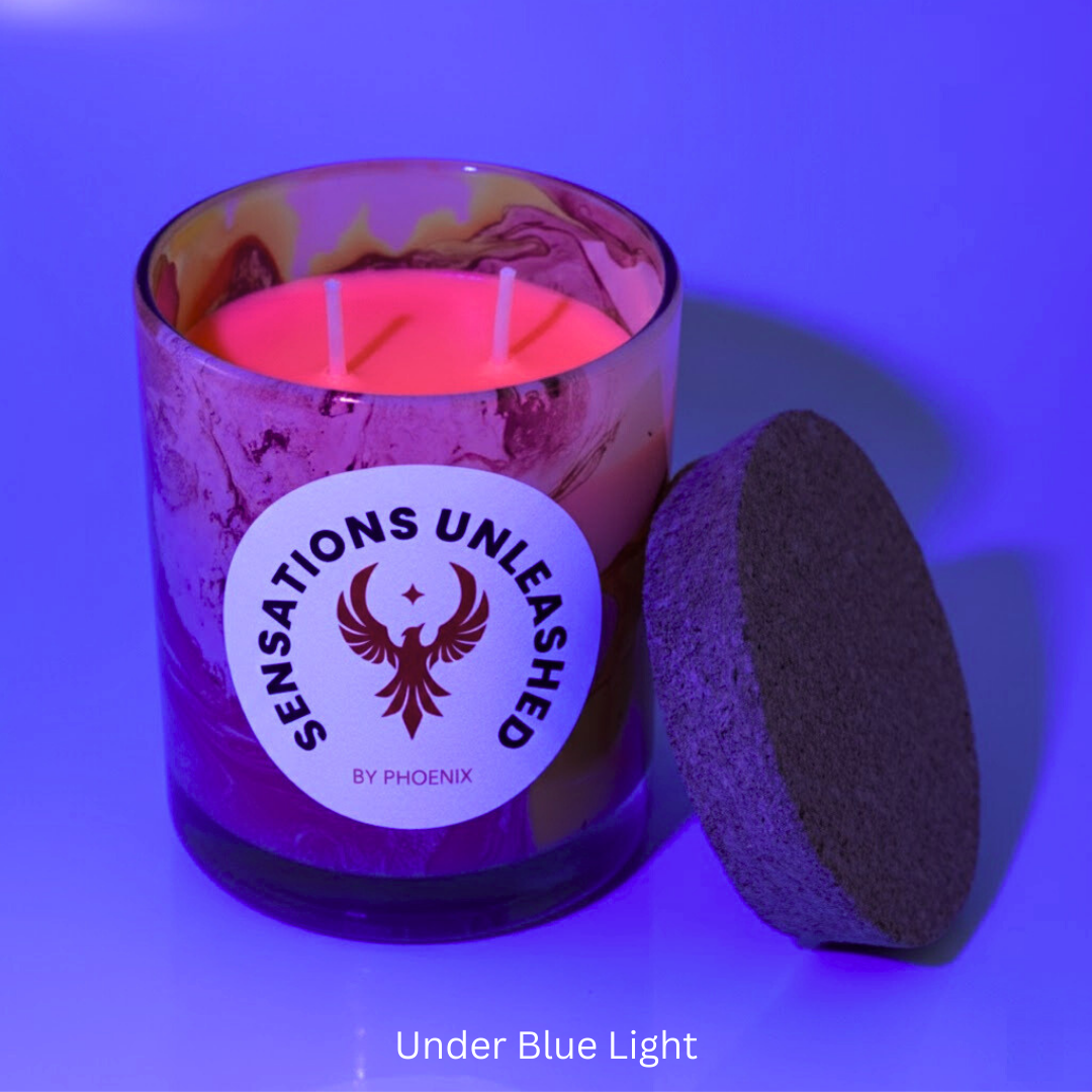 Candle in a purple jar with 'Sensations Unleashed by Phoenix' label, lit under blue light.
Sensations Unleashed BDSM UV Wax Play Glass Jar Candle In India